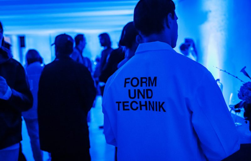 一位男士身着印有“Form und Technik”(形可依,技可循)字样的T恤,置身于蓝光氤氲的展厅。,一位男士身着印有“Form und Technik”(形可依,技可循)字样的T恤,置身于蓝光氤氲的展厅。