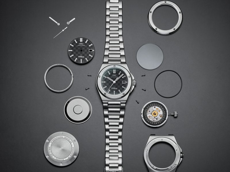Ingenieur Automatic 40 with black dial and stainless steel bracelet, divided into its parts on grey background,Ingenieur Automatic 40 with black dial and stainless steel bracelet, divided into its parts on grey background