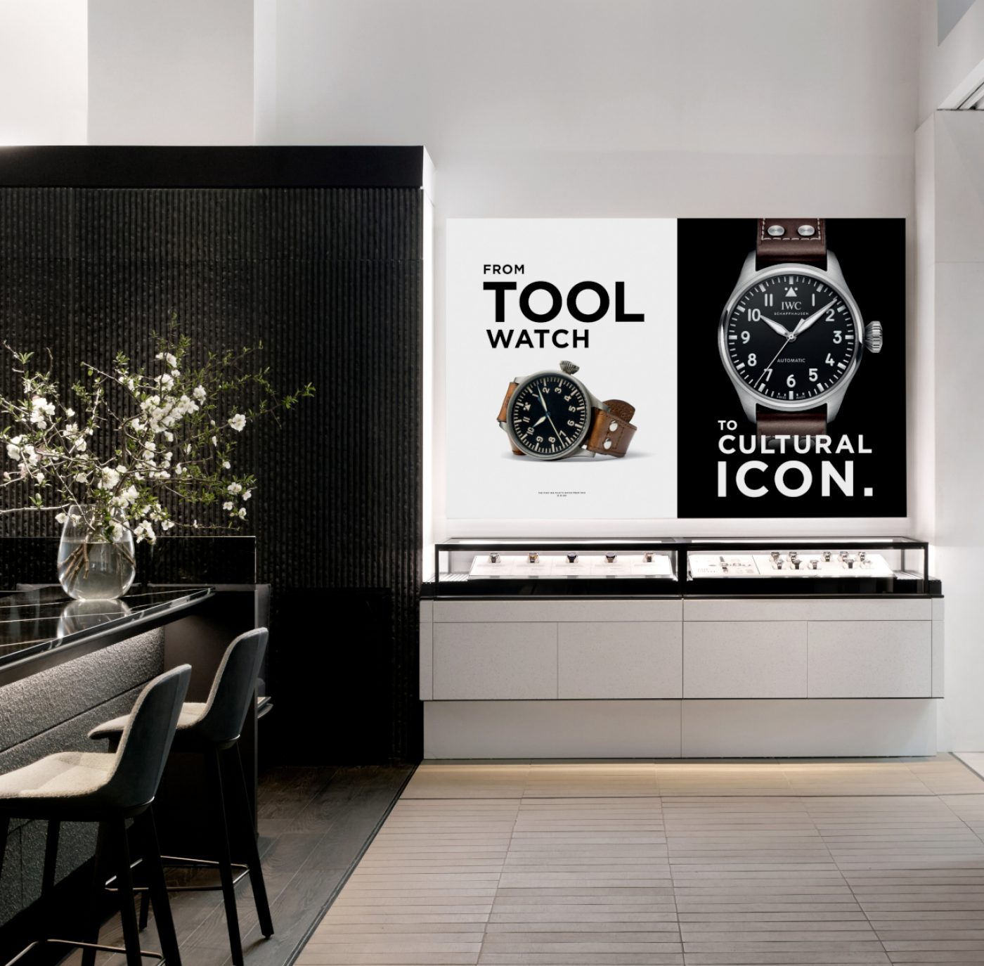 IWC Boutique in Madison Avenue with watch showcase, two watch posters, and a vase of white flowers sitting on a bar to the left