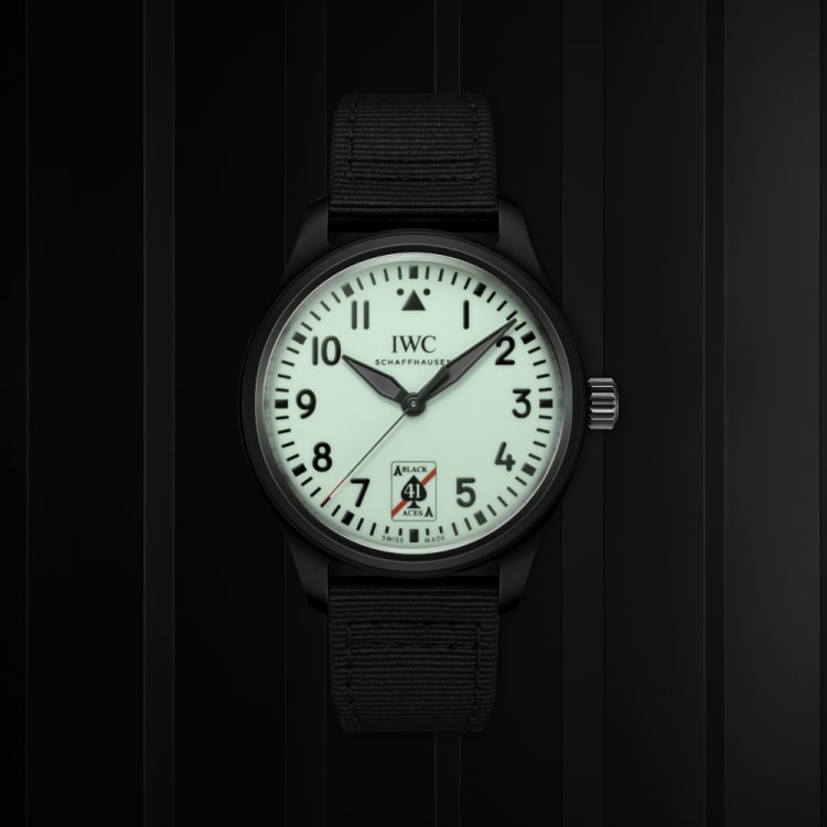 The Pilot’s Watch Automatic 41 Black Aces on a black blackground with low brightness to represent how the dial emits a greenish glow in low-light and dark environments